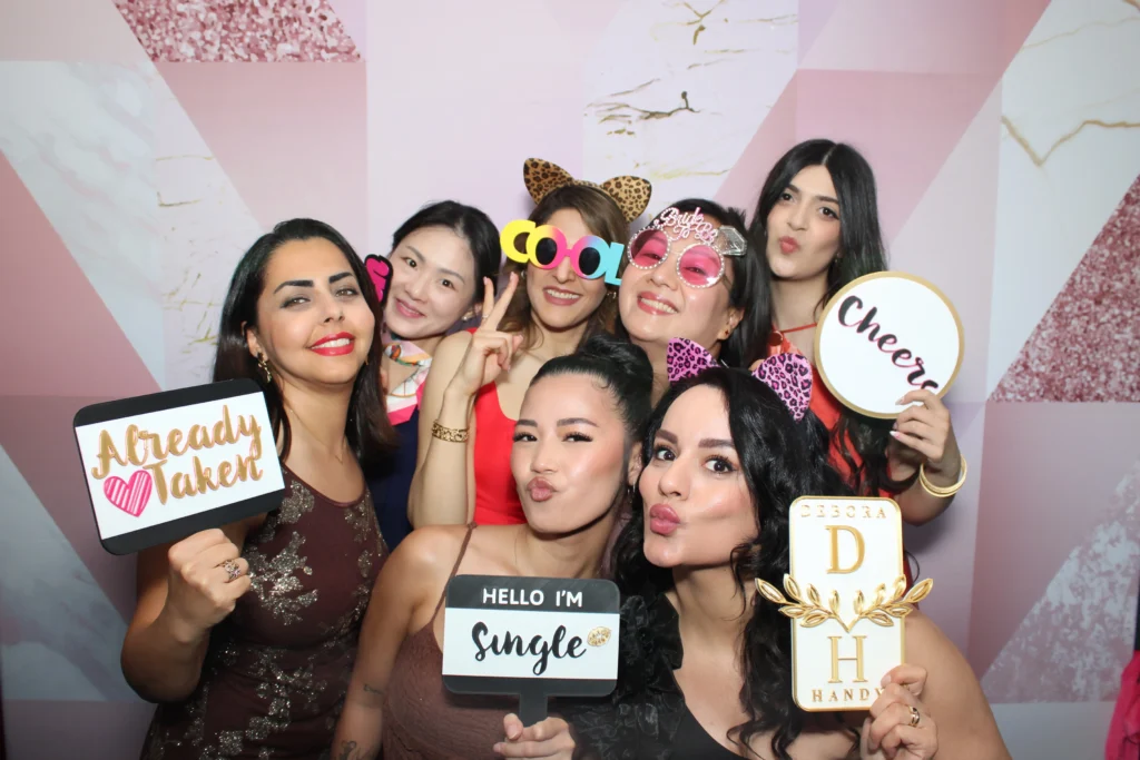Guests at a Prismatic photo booth holding a custom gold initials prop