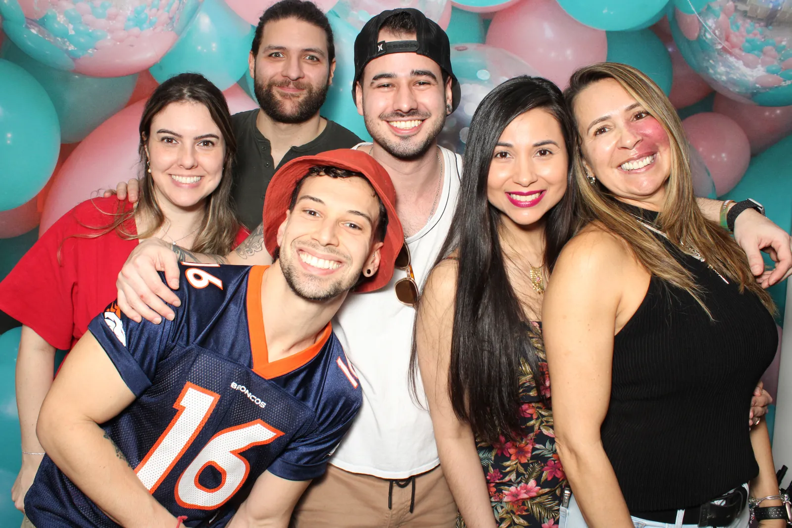 A big group of friends at a Prismatic open-air photo booth with a balloon wall