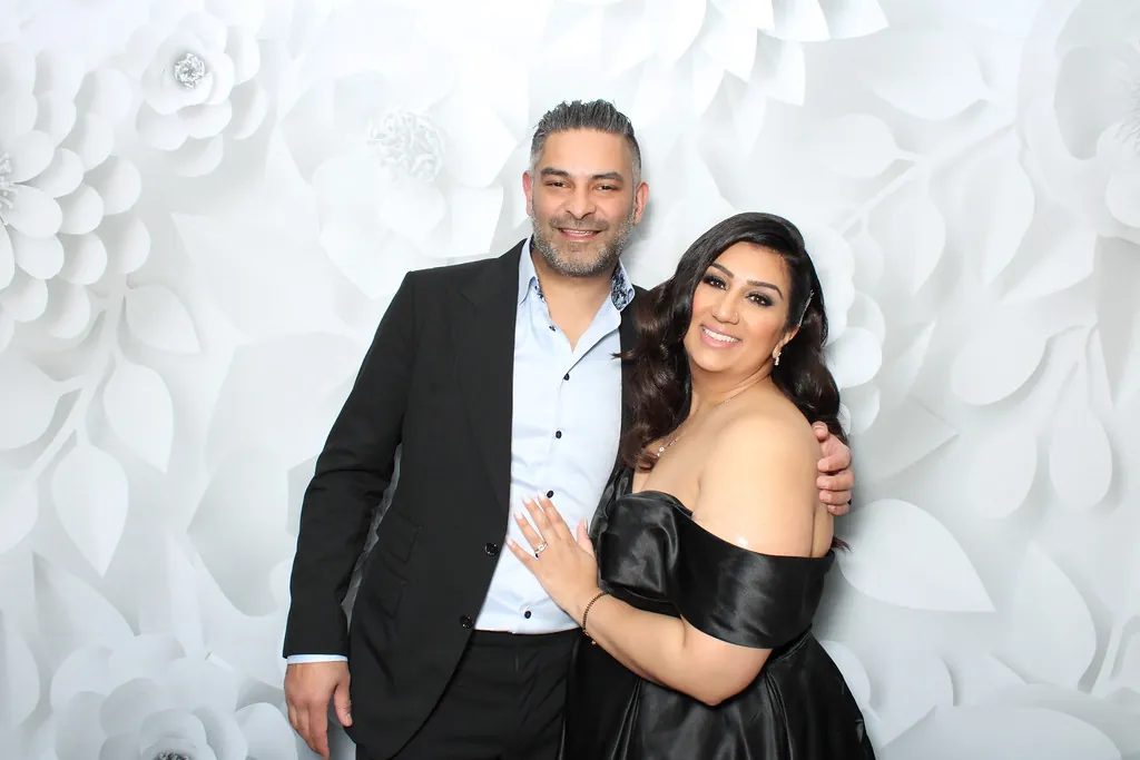 A couple at a Prismatic wedding photo booth with a white floral backdrop