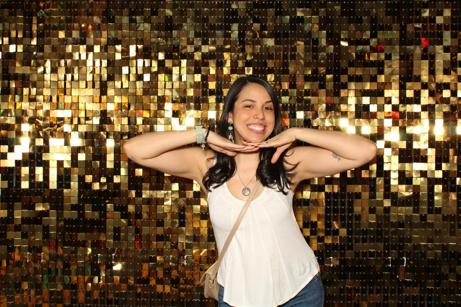 A guest striking a pose at a gold sequin photo booth